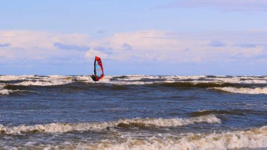 Rüzgarda profesyonel sörfçü okyanusa denizde rüzgar hazırlanıyor. Rüzgar sörfçüsü fırtınada dalgayı yakalar. Konsept: Spor, Yaşam Tarzı, Yönetim Kurulu, Dalgalar, Yavaş Hareket