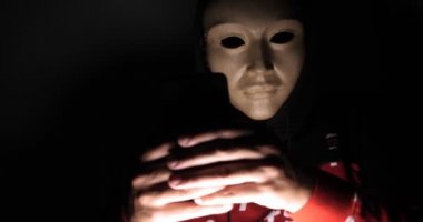 Erkek hacker karanlıkta dizüstü bilgisayar (telefon) kişisel bilgilere erişen maske ile gizli yüz. Teknoloji, siber suç kavramı. 
