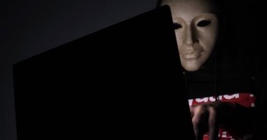Erkek hacker karanlıkta dizüstü bilgisayar (telefon) kişisel bilgilere erişen maske ile gizli yüz. Teknoloji, siber suç kavramı. 