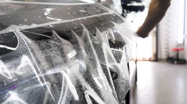Ön far ve kaputta Ppf montaj işlemine yakın. Ppf, boyayı çizilmelerden ve taş yongalarından koruyan bir Boya Koruma Filmidir. Konsept: Koruma, Koruma, Araba, Yeni, İş.
