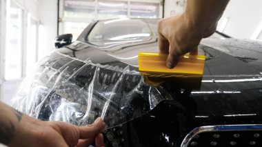 Ön far ve kaputta Ppf montaj işlemine yakın. Ppf, boyayı çizilmelerden ve taş yongalarından koruyan bir Boya Koruma Filmidir. Konsept: Koruma, Koruma, Araba, Yeni, İş.