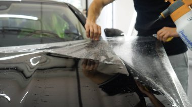 Ön far ve kaputta Ppf montaj işlemine yakın. Ppf, boyayı çizilmelerden ve taş yongalarından koruyan bir Boya Koruma Filmidir. Konsept: Koruma, Koruma, Araba, Yeni, İş.