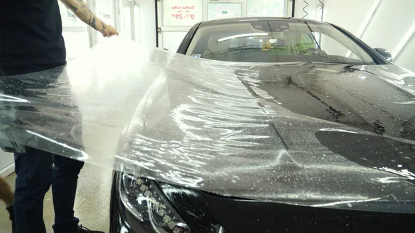 Ön far ve kaputta Ppf montaj işlemine yakın. Ppf, boyayı çizilmelerden ve taş yongalarından koruyan bir Boya Koruma Filmidir. Konsept: Koruma, Koruma, Araba, Yeni, İş.