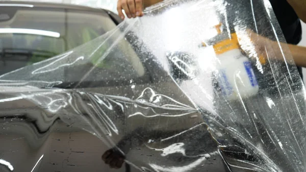 Ön far ve kaputta Ppf montaj işlemine yakın. Ppf, boyayı çizilmelerden ve taş yongalarından koruyan bir Boya Koruma Filmidir. Konsept: Koruma, Koruma, Araba, Yeni, İş.