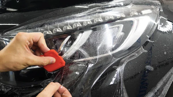 Ön far ve kaputta Ppf montaj işlemine yakın. Ppf, boyayı çizilmelerden ve taş yongalarından koruyan bir Boya Koruma Filmidir. Konsept: Koruma, Koruma, Araba, Yeni, İş.