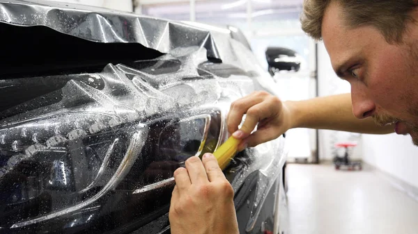 Ön far ve kaputta Ppf montaj işlemine yakın. Ppf, boyayı çizilmelerden ve taş yongalarından koruyan bir Boya Koruma Filmidir. Konsept: Koruma, Koruma, Araba, Yeni, İş.