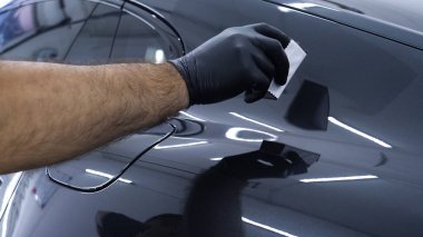 Personel iş yerinde kimyasal koruyucu giysiler giyer. Otomobil endüstrisi. Seramik kaplama ile oto yıkama ve kaplama işi. Vernikleri arabaya püskürtüyor. Konsept: Araba koruyucu, Servis, Shine.