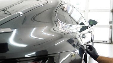 Personel iş yerinde kimyasal koruyucu giysiler giyer. Otomobil endüstrisi. Seramik kaplama ile oto yıkama ve kaplama işi. Vernikleri arabaya püskürtüyor. Konsept: Araba koruyucu, Servis, Shine.