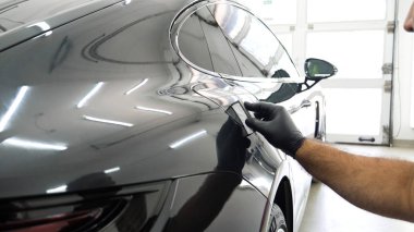 Personel iş yerinde kimyasal koruyucu giysiler giyer. Otomobil endüstrisi. Seramik kaplama ile oto yıkama ve kaplama işi. Vernikleri arabaya püskürtüyor. Konsept: Araba koruyucu, Servis, Shine.