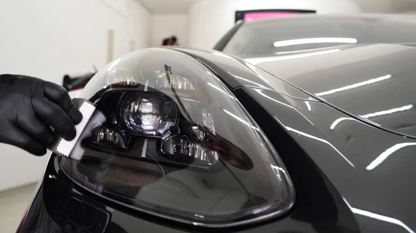 Personel iş yerinde kimyasal koruyucu giysiler giyer. Otomobil endüstrisi. Seramik kaplama ile oto yıkama ve kaplama işi. Vernikleri arabaya püskürtüyor. Konsept: Araba koruyucu, Servis, Shine.