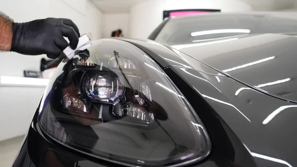 Personel iş yerinde kimyasal koruyucu giysiler giyer. Otomobil endüstrisi. Seramik kaplama ile oto yıkama ve kaplama işi. Vernikleri arabaya püskürtüyor. Konsept: Araba koruyucu, Servis, Shine.