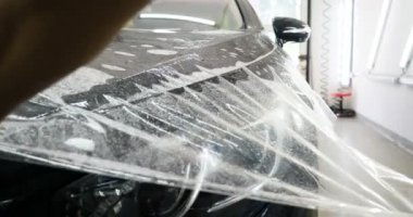 Ön far ve kaputta Ppf montaj işlemine yakın. Ppf, boyayı çizilmelerden ve taş yongalarından koruyan bir Boya Koruma Filmidir. Konsept: Koruma, Koruma, Araba, Yeni, İş.