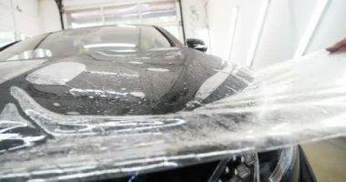 Ön far ve kaputta Ppf montaj işlemine yakın. Ppf, boyayı çizilmelerden ve taş yongalarından koruyan bir Boya Koruma Filmidir. Konsept: Koruma, Koruma, Araba, Yeni, İş.