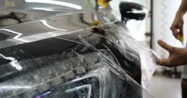 Ön far ve kaputta Ppf montaj işlemine yakın. Ppf, boyayı çizilmelerden ve taş yongalarından koruyan bir Boya Koruma Filmidir. Konsept: Koruma, Koruma, Araba, Yeni, İş.