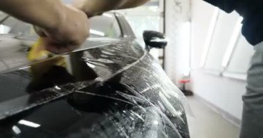 Ön far ve kaputta Ppf montaj işlemine yakın. Ppf, boyayı çizilmelerden ve taş yongalarından koruyan bir Boya Koruma Filmidir. Konsept: Koruma, Koruma, Araba, Yeni, İş.