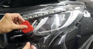 Ön far ve kaputta Ppf montaj işlemine yakın. Ppf, boyayı çizilmelerden ve taş yongalarından koruyan bir Boya Koruma Filmidir. Konsept: Koruma, Koruma, Araba, Yeni, İş.
