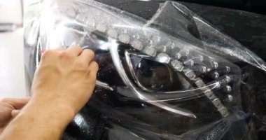 Ön far ve kaputta Ppf montaj işlemine yakın. Ppf, boyayı çizilmelerden ve taş yongalarından koruyan bir Boya Koruma Filmidir. Konsept: Koruma, Koruma, Araba, Yeni, İş.
