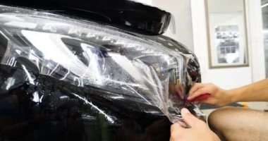 Ön far ve kaputta Ppf montaj işlemine yakın. Ppf, boyayı çizilmelerden ve taş yongalarından koruyan bir Boya Koruma Filmidir. Konsept: Koruma, Koruma, Araba, Yeni, İş.