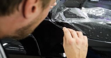 Ön far ve kaputta Ppf montaj işlemine yakın. Ppf, boyayı çizilmelerden ve taş yongalarından koruyan bir Boya Koruma Filmidir. Konsept: Koruma, Koruma, Araba, Yeni, İş.