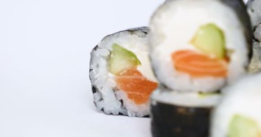 Bir veya daha fazla maki rulo somon, avokado, ton balığı ve salatalık beyaz arka planda izole bir satırda. Pirinç ve Nori ile taze hosomaki parçaları. Suşi rulo ile lezzetli Japon gıda closeup.