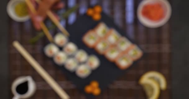 サーモンとマグロ カリフォルニアロールス 醤油クローズアップの寿司セットをテーブルの上に提供 手は箸で寿司を食べる — ストック動画