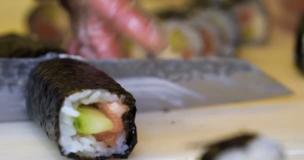店内のキッチンで寿司や巻き寿司を作る透明手袋でプロのシェフの手のクローズアップ 日本の伝統料理 準備プロセスだ コンセプト ローリング サラモン — ストック動画