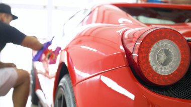 Araba merkezinde (garajda), profesyoneller yeni bir spor araba Lehçe. Lüks araba parlatma. Kavramı: yarış, spor araba, yeni, yavaş hareket, NASCAR, kırmızı, krom kaplama.