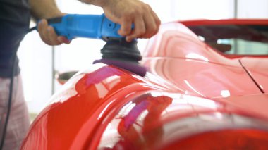 Araba merkezinde (garajda), profesyoneller yeni bir spor araba Lehçe. Lüks araba parlatma. Kavramı: yarış, spor araba, yeni, yavaş hareket, NASCAR, kırmızı, krom kaplama.