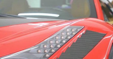 Araba merkezinde (garajda), profesyoneller yeni bir spor araba Lehçe. Lüks araba parlatma. Kavramı: yarış, spor araba, yeni, yavaş hareket, NASCAR, kırmızı, krom kaplama.
