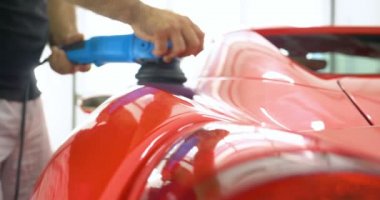 Araba merkezinde (garajda), profesyoneller yeni bir spor araba Lehçe. Lüks araba parlatma. Kavramı: yarış, spor araba, yeni, yavaş hareket, NASCAR, kırmızı, krom kaplama.
