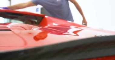 Araba merkezinde (garajda), profesyoneller yeni bir spor araba Lehçe. Lüks araba parlatma. Kavramı: yarış, spor araba, yeni, yavaş hareket, NASCAR, kırmızı, krom kaplama.