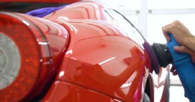 Araba merkezinde (garajda), profesyoneller yeni bir spor araba Lehçe. Lüks araba parlatma. Kavramı: yarış, spor araba, yeni, yavaş hareket, NASCAR, kırmızı, krom kaplama.