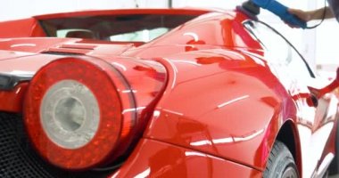 Araba merkezinde (garajda), profesyoneller yeni bir spor araba Lehçe. Lüks araba parlatma. Kavramı: yarış, spor araba, yeni, yavaş hareket, NASCAR, kırmızı, krom kaplama.