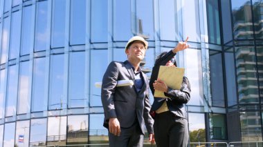 Mimarlar takımı ve inşaat sahasındaki belgeleri ve iş akışını kontrol eden bir grup mühendis. Mimari plan için işyerinde mühendis teftişi. Kadın, Erkek, Süit, İş Konsepti.