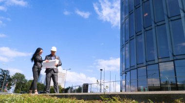 Mimarlar takımı ve inşaat sahasındaki belgeleri ve iş akışını kontrol eden bir grup mühendis. Mimari plan için işyerinde mühendis teftişi. Kadın, Erkek, Süit, İş Konsepti.