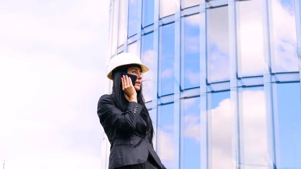 Happiness businesswoman calling by phone on the business architecture background. Concept of: Skyscraper, Business girl, Architect, Lifestyle.