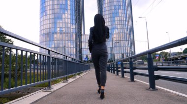 İş kadını köprü üzerinde şehir iş merkezinde yürümek. Genç iş kadını köprü üzerinde şehir iş merkezinde yürümek. Konsept: Kadın, Gökdelen, İş, Yaşam Tarzı.