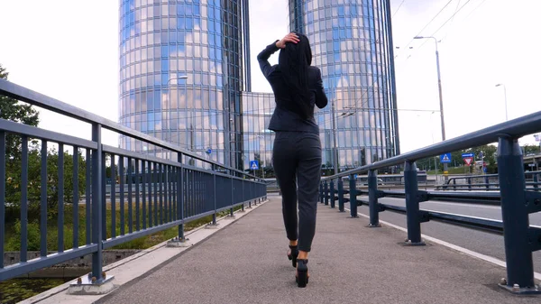 Business woman walk in city business center over bridge. Young business woman walk in city business center over bridge. Concept of: Woman, Skyscraper, Work, Lifestyle.