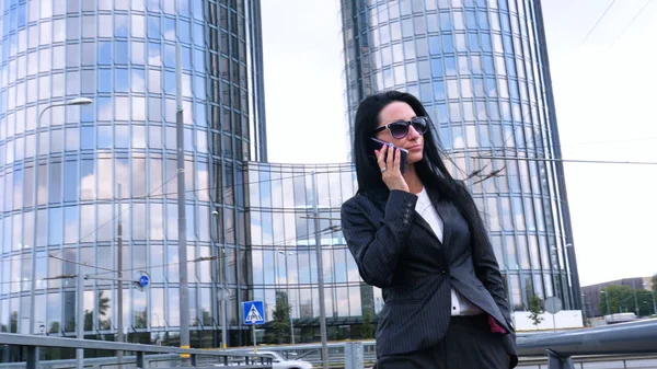 Happiness businesswoman calling by phone on the business architecture background. Concept of: Skyscraper, Business girl, Architect, Lifestyle.