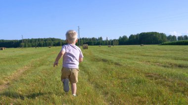 Şort sevimli küçük çocuk alan boyunca çalışır ve bir samanlık ve mısır alanı etrafında bir oyuncak uçak başlattı. Kavramı: Oyun, Yaz, Alan, Eko, Mutlu.
