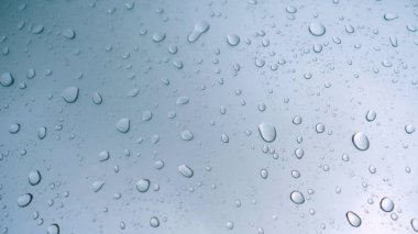 Araba cam arka plan üzerinde yağmur damla. Yağmur damlaları ile araba penceresinden yol manzarası, yağmurda sürüş. Yağmur gününde soyut trafik. Araba koltuğundan bak. Konsept: Sürücü, Hızlı, Yalnız, Araba, Yakın Çekim.