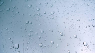 Araba cam arka plan üzerinde yağmur damla. Yağmur damlaları ile araba penceresinden yol manzarası, yağmurda sürüş. Yağmur gününde soyut trafik. Araba koltuğundan bak. Konsept: Sürücü, Hızlı, Yalnız, Araba, Yakın Çekim.