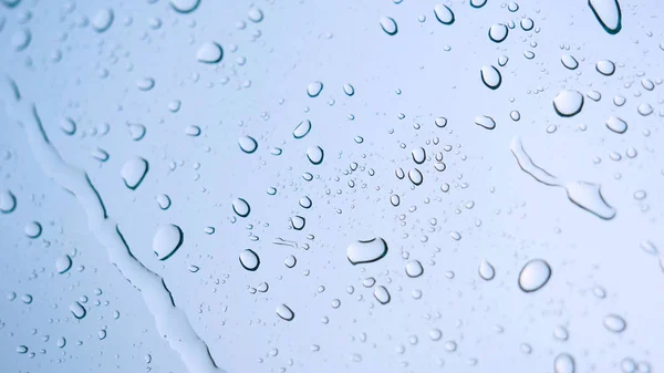 Rain drop on the car glass background.Road view through car window with rain drops, Driving in rain. Abstract traffic in raining day. View from car seat. Concept of: Drive, Fast, Alone, Car, Close up.