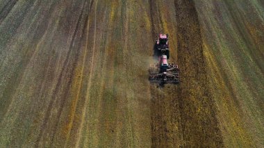 Hasat alanının hava görüntülü dronu traktörle kuru çim biçiyor. Sonbahar sarı tarlası ve hasat sonrası saman yığını. Harves. Tarlalarda karıncalanma. Stok yap.