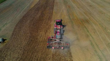 Hasat alanının hava görüntülü dronu traktörle kuru çim biçiyor. Sonbahar sarı tarlası ve hasat sonrası saman yığını. Harves. Tarlalarda karıncalanma. Stok yap.