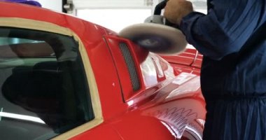 İşçi araba cilasıyla araba cilalıyor. Çalışanların ellerini oto cilalayıcı kullanarak atölyedeki araba gövdesini parlatmak için kapatın.