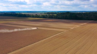Hasat alanının hava görüntülü dronu traktörle kuru çim biçiyor. Sonbahar sarı tarlası ve hasat sonrası saman yığını. Harves. Tarlalarda karıncalanma. Stok yap.