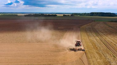 Hasat alanının hava görüntülü dronu traktörle kuru çim biçiyor. Sonbahar sarı tarlası ve hasat sonrası saman yığını. Harves. Tarlalarda karıncalanma. Stok yap.