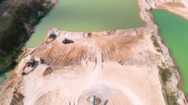 Ariel Excavator 'un bulutlu ama güneşli bir günde bir inşaat sahasına park edilmiş görüntüsü..