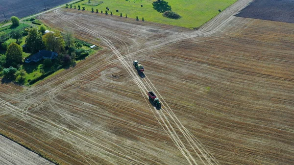 Aerial shot of harvester loading off corn on trailers. Aerial shot of modern harvester loading off corn on tractor trailers. Concept of: Tractor, Harvest, Drone, Eco.